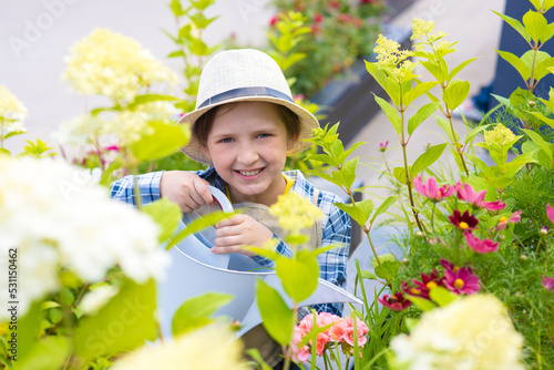 portrait of a smiling boy in a hat and apron in a blooming garden