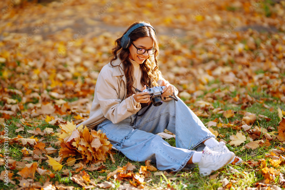 Portrait of beautiful woman taking pictures in the autumn forest. Smiling woman enjoying autumn weather. Rest, relaxation, lifestyle concept. Portrait of beautiful woman taking pictures in the autumn forest. Smiling woman enjoying autumn weather. Rest, relaxation, lifestyle concept.