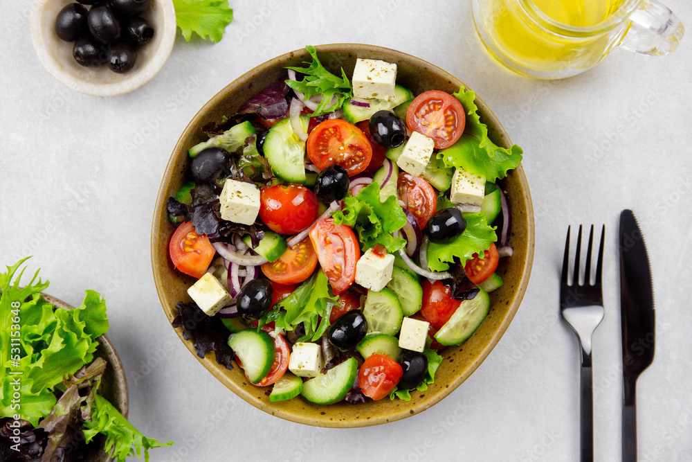 Fresh greek salad with cherry tomato, cucumber, lettuce, black olive, feta cheese and olives oil on gray concrete background. Fresh greek salad with cherry tomato, cucumber, lettuce, black olive, feta cheese and olives oil on gray concrete background.