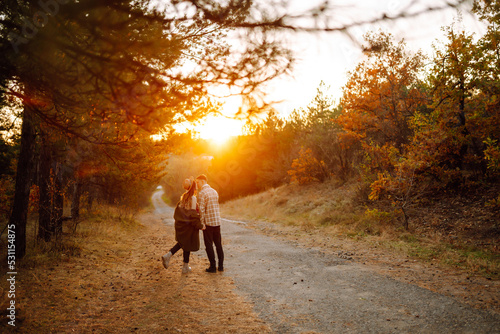 Young couple having fun walking and hugging on autumn park at sunset. People, lifestyle, relaxation and vacations concept.