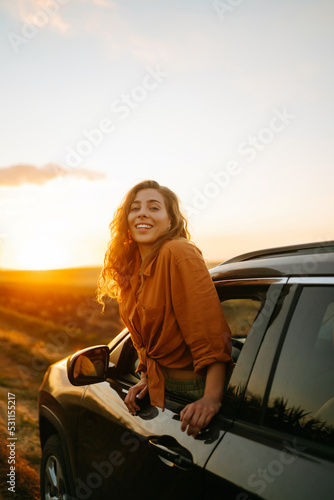 Young woman is resting and enjoying sunset in the car. Lifestyle, travel, tourism, nature, active life. © maxbelchenko