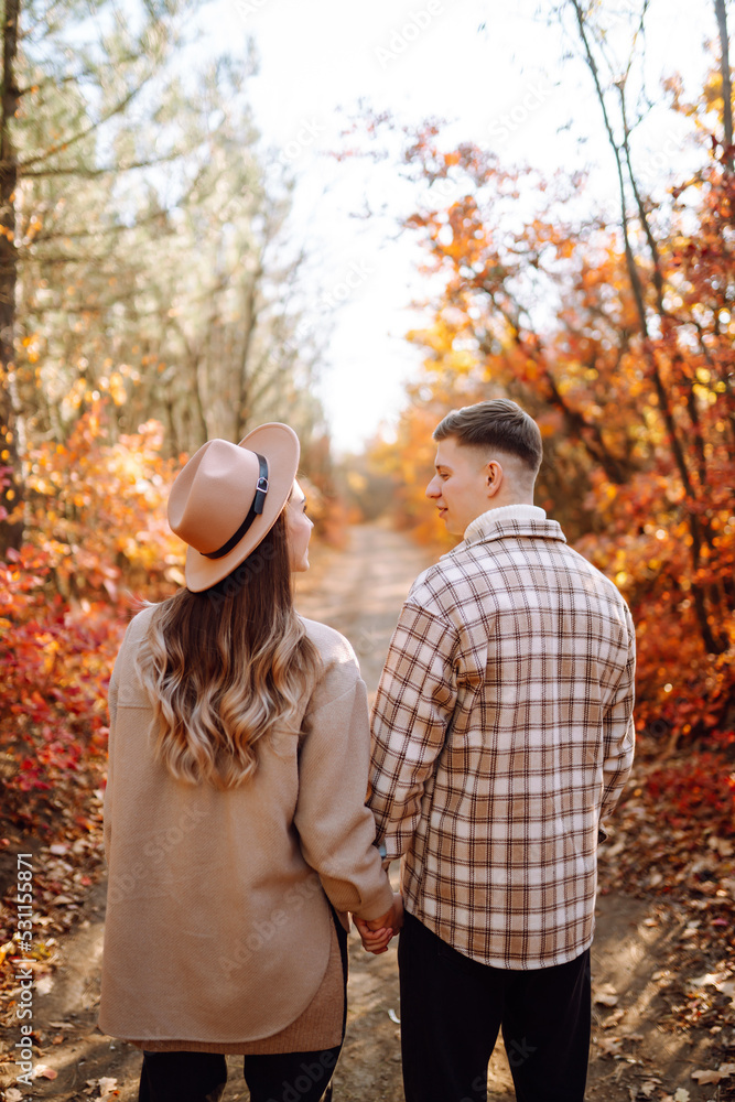 Naklejka premium Young couple in love walking in the park on a autumn day. Enjoying time together.