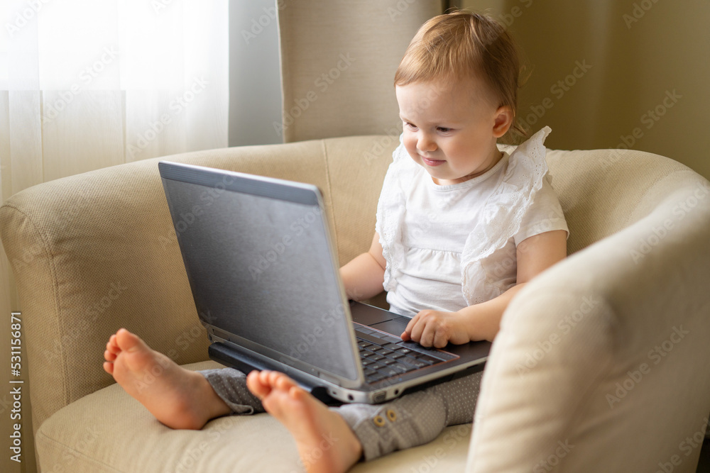A baby in a light chair sits at a laptop and spoils his eyesight, watching cartoons A baby in a light chair sits at a laptop and spoils his eyesight, watching cartoons