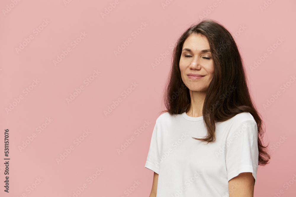 a beautiful cute attractive woman stands on a beige background with long hair, with closed eyes. a beautiful cute attractive woman stands on a beige background with long hair, with closed eyes.