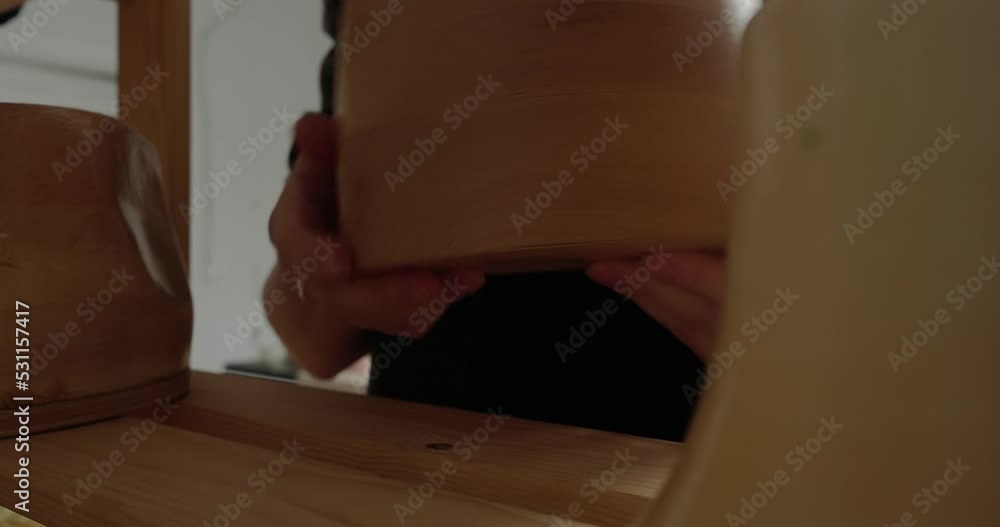 Professional milliner takes wooden mold standing on shelf Professional milliner takes wooden mold standing on shelf