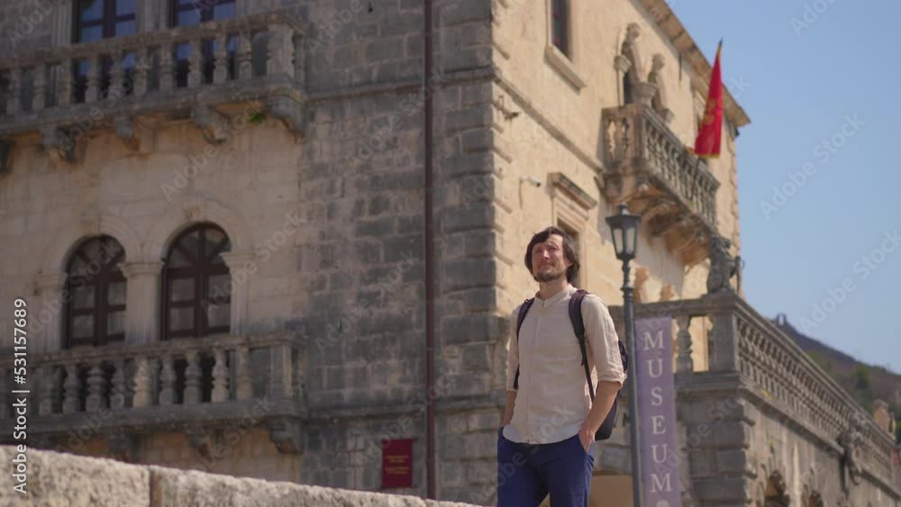 A young man is walking along the shore of the city of Perast, a beautiful coastal town in the Boka-Kotorska bay A young man is walking along the shore of the city of Perast, a beautiful coastal town in the Boka-Kotorska bay