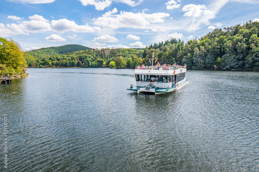 Boat with tourists on Lake Rursee, In the middle of the Eifel National Park, surrounded by unique natural scenery and unspoilt nature Boat with tourists on Lake Rursee, In the middle of the Eifel National Park, surrounded by unique natural scenery and unspoilt nature