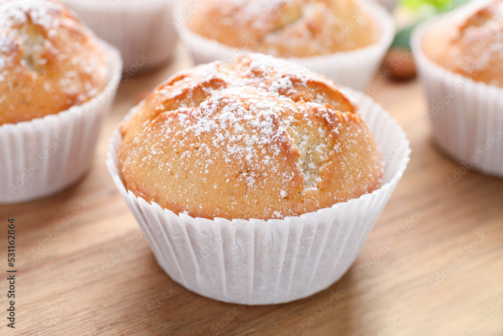 Tasty muffins powdered with sugar on wooden board, closeup Tasty muffins powdered with sugar on wooden board, closeup