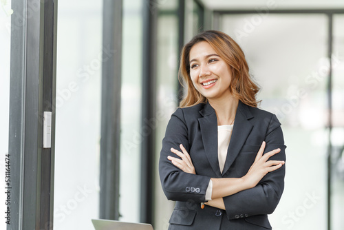 Free Download Cheerful asian businesswoman sitting at the table in office and looking out of windows feeling happy.. - GFXLoad