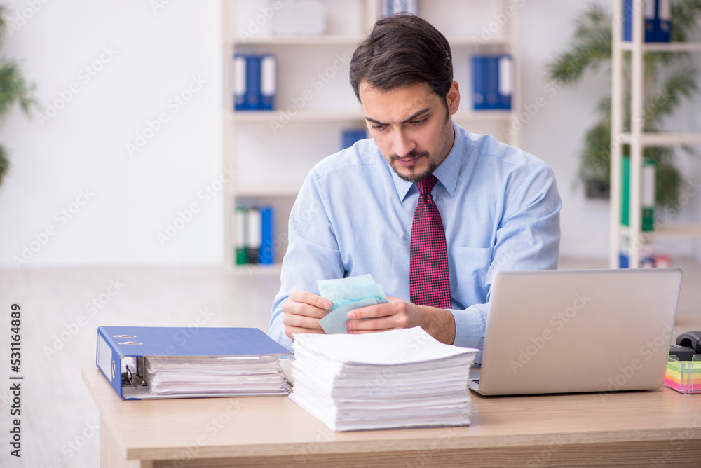 Young male employee and too much work in the office Young male employee and too much work in the office