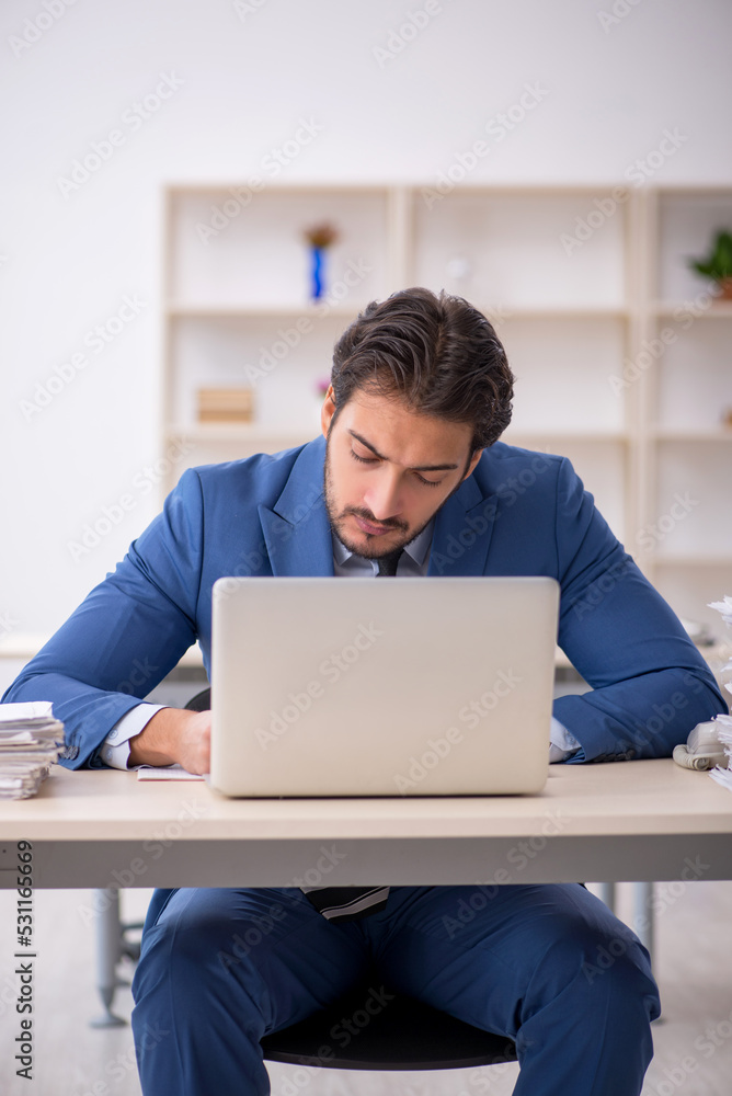 Young male employee and too much work in the office Young male employee and too much work in the office