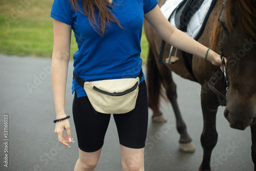 Girl holding horse. Belt bag. Blue t-shirt. Holding horse.