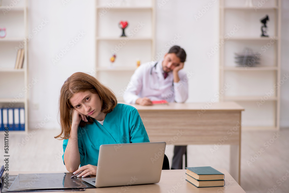 Young male doctor and female assistant working in the clinic Young male doctor and female assistant working in the clinic