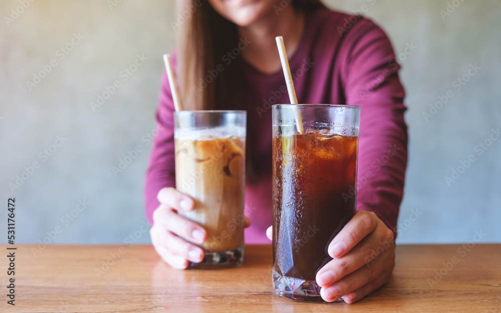 Closeup image of a young woman holding and serving two glasses of iced coffee Closeup image of a young woman holding and serving two glasses of iced coffee