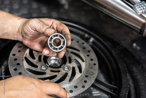 Mechanic check and replace Motorcycle wheel bearings , working in garage . repair and  maintenance motorcycle concept .selective focus photo