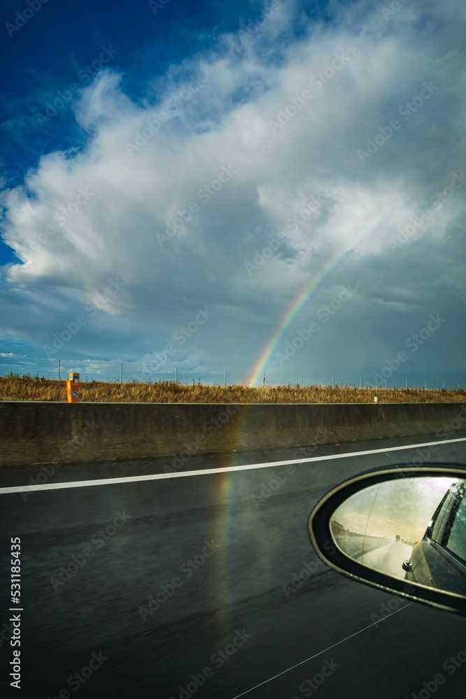 Fototapeta premium View of road from car with rainbow in sky