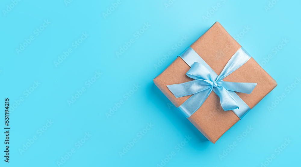 Gift box with a blue ribbon on a blue background. The concept of holidays. Top view, horizontal Gift box with a blue ribbon on a blue background. The concept of holidays. Top view, horizontal