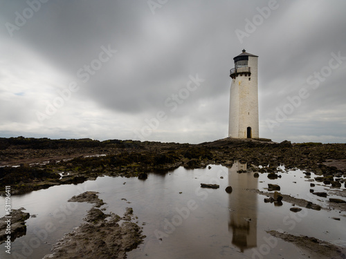 the historic Southerness Lighthouse in Scotland with reflections in tidal pools in the foreground
