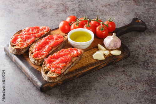 Spanish tomato toast pan tomaca or tostadas con tomate closeup on the wooden board on the table. Horizontal photo