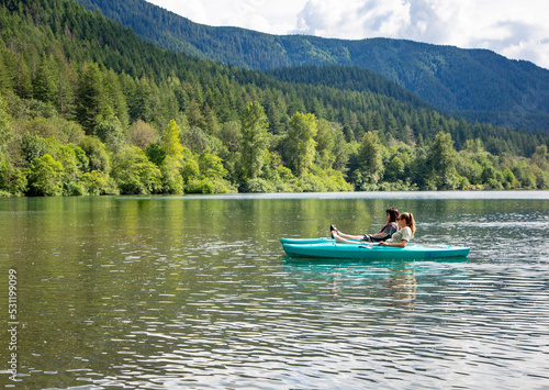 Two women Kayaking on a pristine mountain lake in the state of Washington Pacific Northwest. Scenic landscape horizontal photo of two friends enjoying the great outdoors together photo