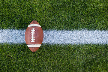 View from above of an American Football sitting on a grass football field on the yard line. Generic Sports image. Lots of Copy space