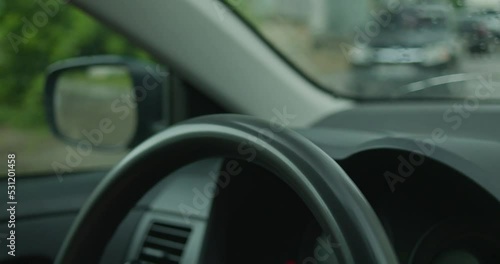 Close up of a young woman's hands on the steering wheel of a car while she is driving. A woman is driving a car around the city, her hands move along the steering wheel. The movement of the car takes