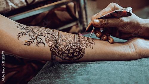 Henna tattoo apply on a bride hands. Elegant Brown Colors of Henna Ink. Indian Traitional Mehendi Ceremony. photo