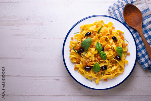 Pasta ribbons with sautéed pumpkin and black olives. Traditional Italian recipe.