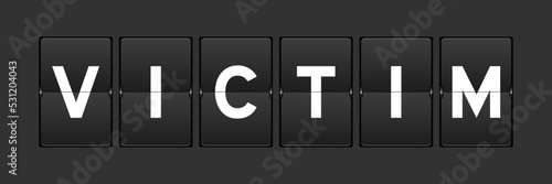 Black color analog flip board with word victim on gray background