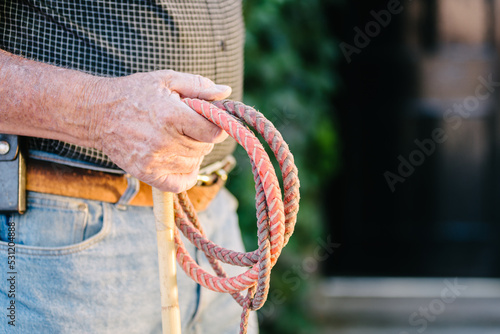 old retired cowboy holding a whip photo