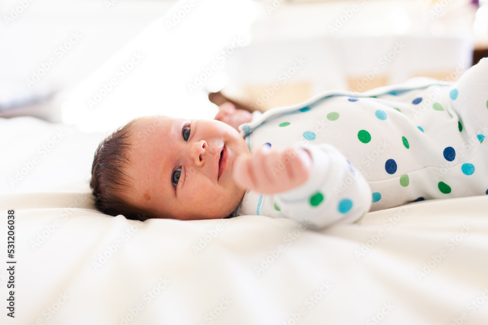 Happy young newborn baby lying on parents bed in bedroom - morning time Happy young newborn baby lying on parents bed in bedroom - morning time
