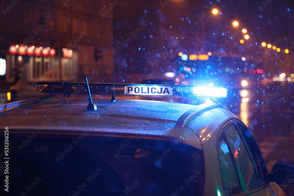 Polska policja na służbie zimą w czasie opadów śniegu wieczorem.  - obrazy, fototapety, plakaty 