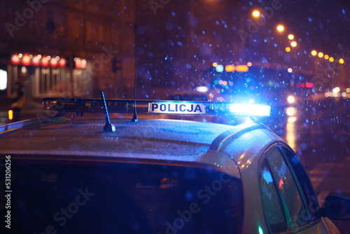 Polska policja na służbie zimą w czasie opadów śniegu wieczorem. 