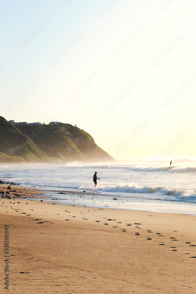 Man fishing in the Ocean at Burwood Beach, New South Wales, Australia during Sunset