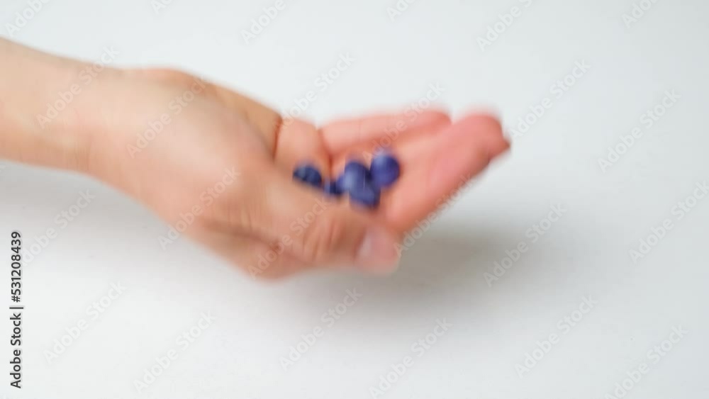 A woman's hand tosses blue pills up on a blue background, close-up A woman's hand tosses blue pills up on a blue background, close-up