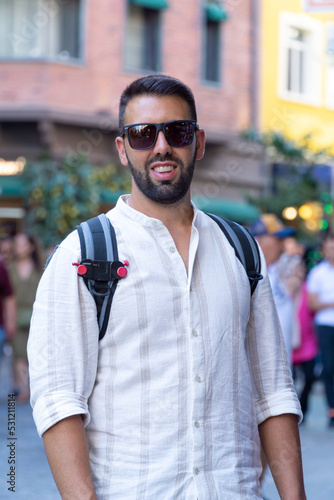 Portrait of a young man with beard and sunglasses in the foreground with the background out of focus. © ANGEL LARA FOTO