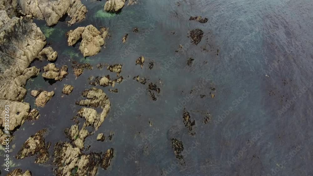 Rocky seashore, top view. Calm water surface, small ripples on the water. Rocky seashore, top view. Calm water surface, small ripples on the water.