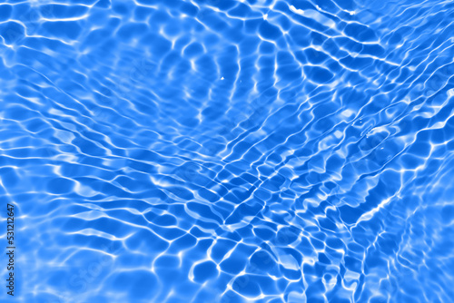 Bluewater waves on the surface ripples blurred. Defocus blurred transparent blue colored clear calm water surface texture with splash and bubbles. Water waves with shining pattern texture background.