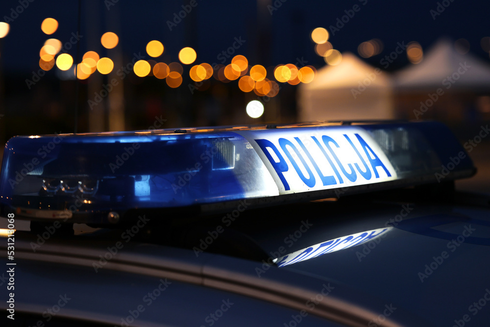 Nocna interwencja alarmowa policji - Sygnalizator błyskowy niebieski na dachu radiowozu policji polskiej w nocy. - obrazy, fototapety, plakaty 