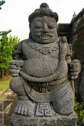 Vertical shot of a Hindu stone statue of a Gate Guardian Gupolo in Indonesia photo