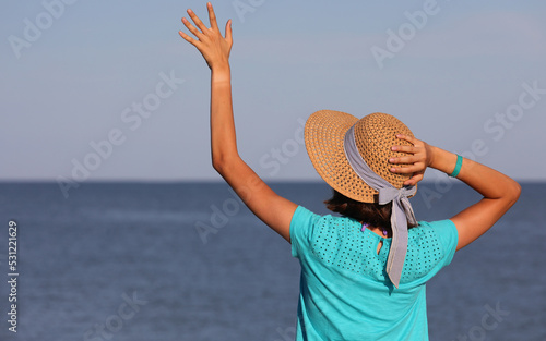 young girl with boater straw hat by the sea during summer vacation photo