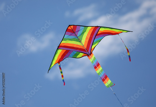 kite with the many colors of the rainbow flying high attached to a string