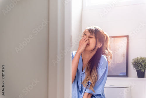 asian woman having stomach ache pain in toilet. ill painful adult unhappy woman desperate from smelly nasty urine or poop. sick unpleasant female weak person sitting using toilet seat urinate in pain