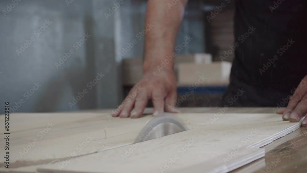 A factory worker cuts a tree with a circular saw. Sawdust of plywood is flying A factory worker cuts a tree with a circular saw. Sawdust of plywood is flying