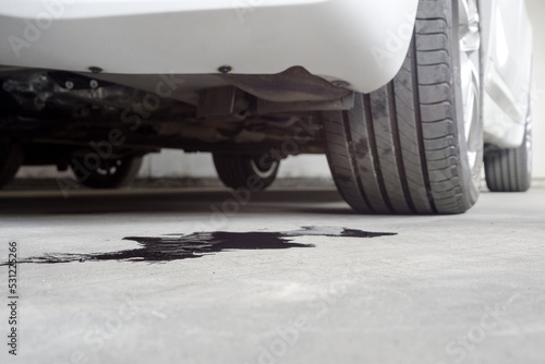 Selective focus of Engine oil stains of car Leaking under the car on blurred Car parked background.