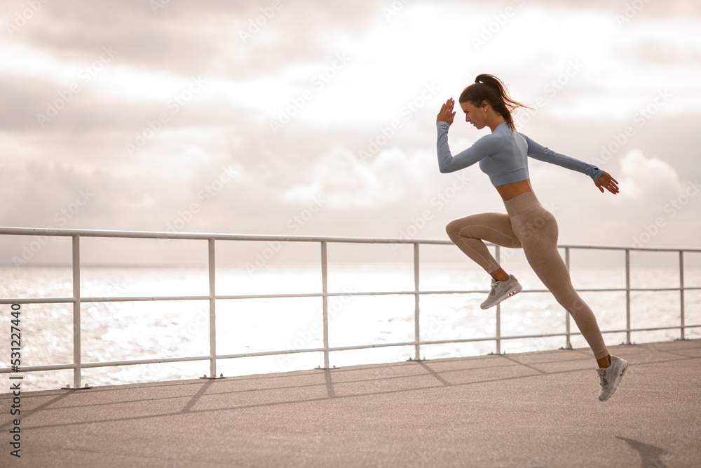 amazing shot of one caucasian woman running and jumping. Female exercising outdoors. amazing shot of one caucasian woman running and jumping. Female exercising outdoors.