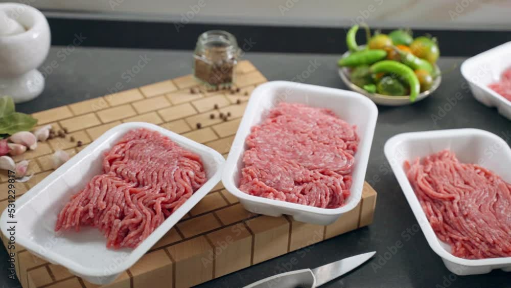 Camera moving along the trendy kitchen table with assortment of ingredients for cooking, raw mince in plastic containers prepared for making hamburgers with steel metal press. Fresh vegetables and Camera moving along the trendy kitchen table with assortment of ingredients for cooking, raw mince in plastic containers prepared for making hamburgers with steel metal press. Fresh vegetables and