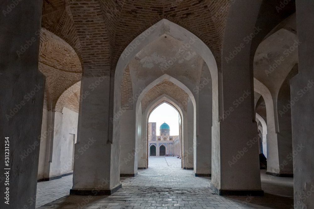 Empty colonnade covered with arched roof in the courtyard of ancient mosque, Bukhara, Uzbekistan