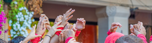 CAMBRILS, SPAIN - SEPTEMBER 04.2022: Hands at a Castells Performance, a castell is a human tower built traditionally in festivals, panorama photo