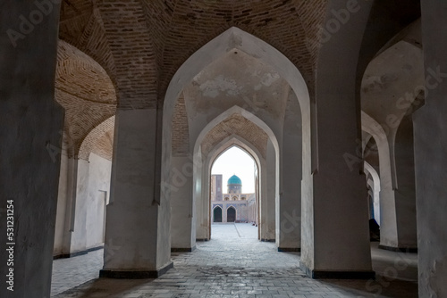 Empty colonnade covered with arched roof in the courtyard of ancient mosque  Bukhara  Uzbekistan